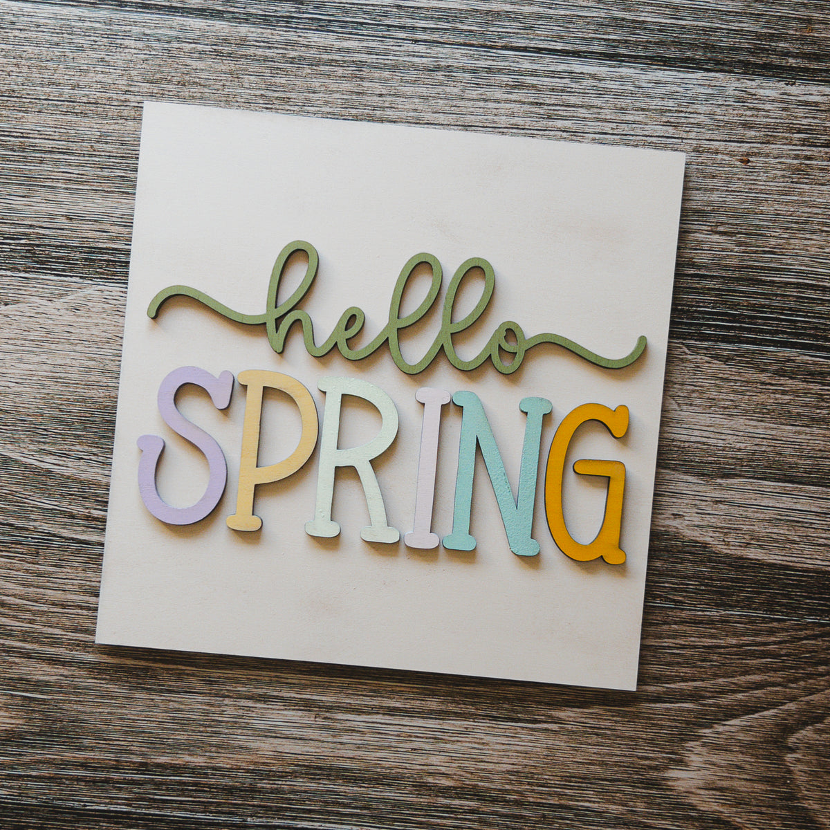 Spring porch decor tile with hello SPRING in pastel block letters on cream wood, Millie & Co.