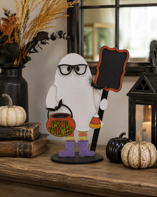 Hand-painted ghost stander in glasses holding a bat bucket and chalkboard countdown sign, displayed on a console table with pumpkins and a lantern