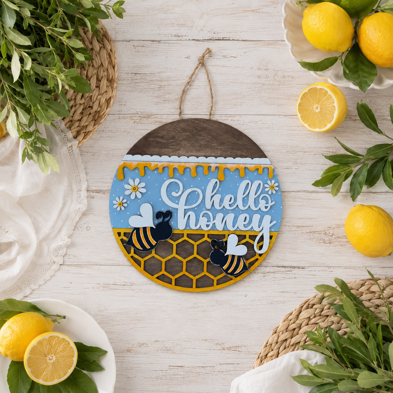 Hand-painted Hello Honey door round with bee and honeycomb design displayed on a wood surface surrounded by fresh lemons