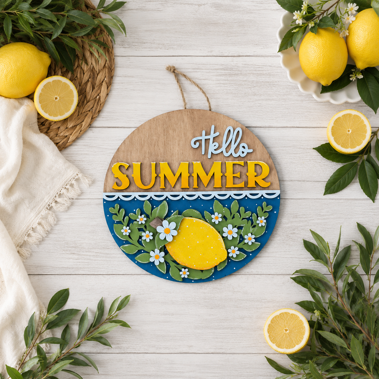 Hand-painted Hello Summer door round with lemon and daisy design displayed on a wood surface surrounded by fresh lemons and greenery