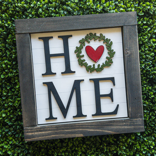 Interchangeable porch decor tile with HOME lettering and a wreath and heart on white shiplap | Millie & Co.