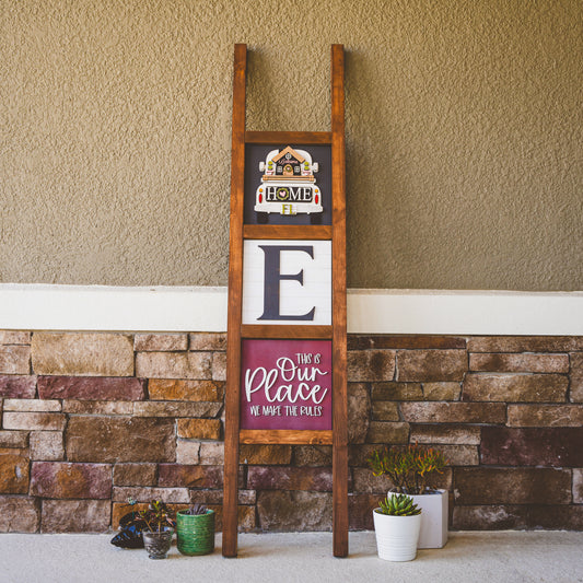 Interchangeable porch ladder with seasonal tiles leaning against a stone wall — Millie & Co.
