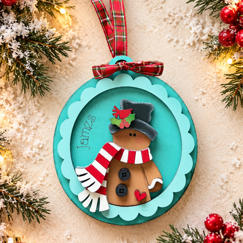 Personalized gingerbread man ornament with name engraved, top hat with cardinal and striped scarf, teal scalloped frame, hand-painted by Millie & Co.