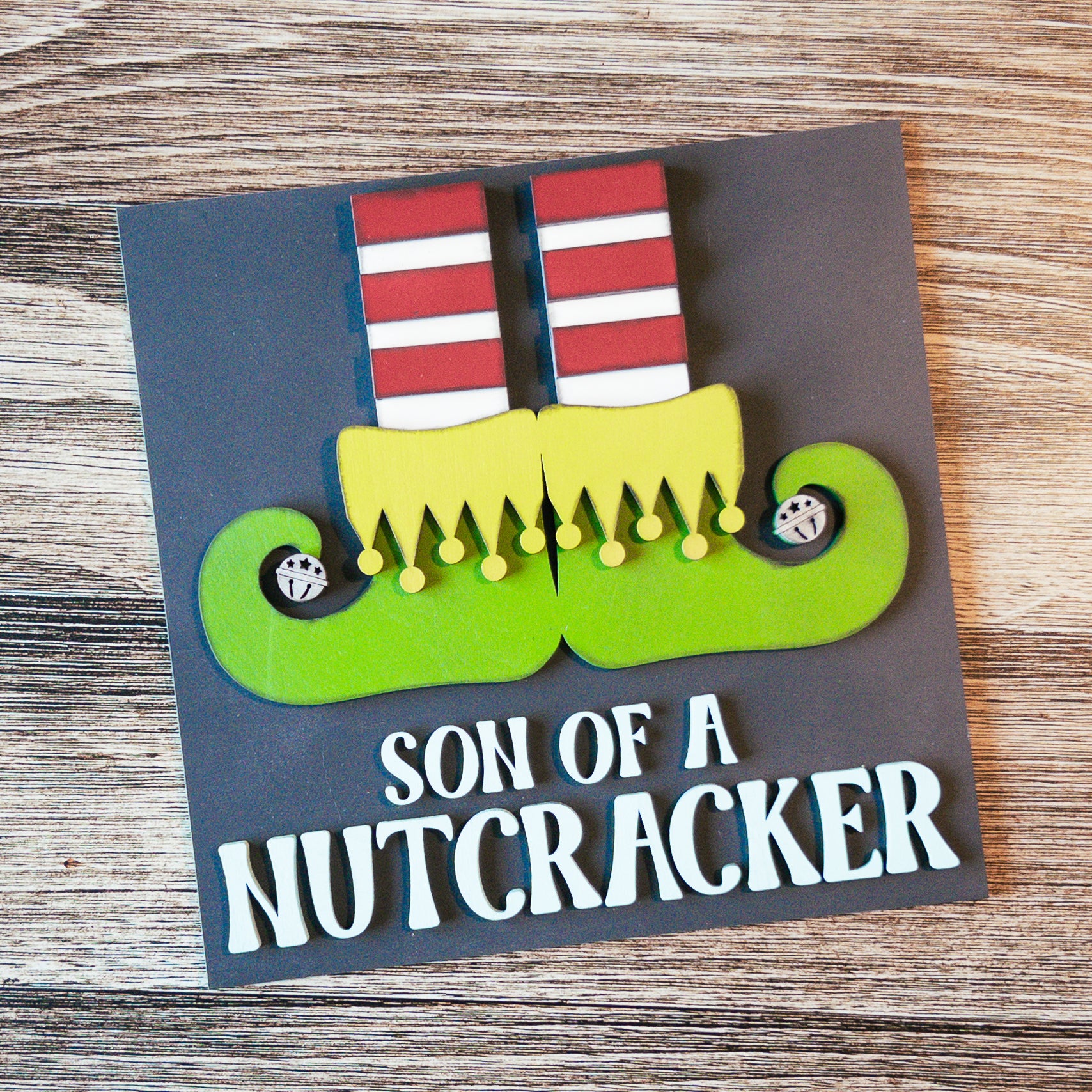 hand-painted interchangeable Christmas tile featuring a playful nutcracker with elf shoes - Millie & Co.