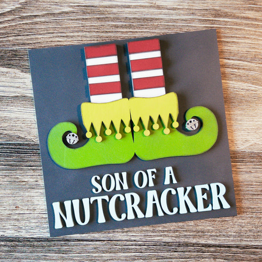 hand-painted interchangeable Christmas tile featuring a playful nutcracker with elf shoes - Millie & Co.