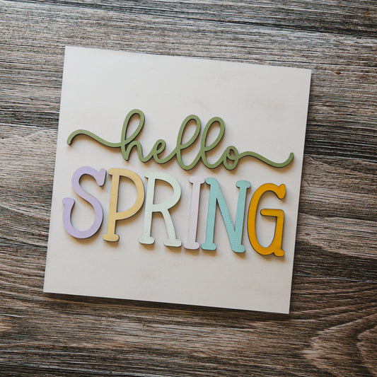 Spring porch decor tile with hello SPRING in pastel block letters on cream wood, Millie & Co.