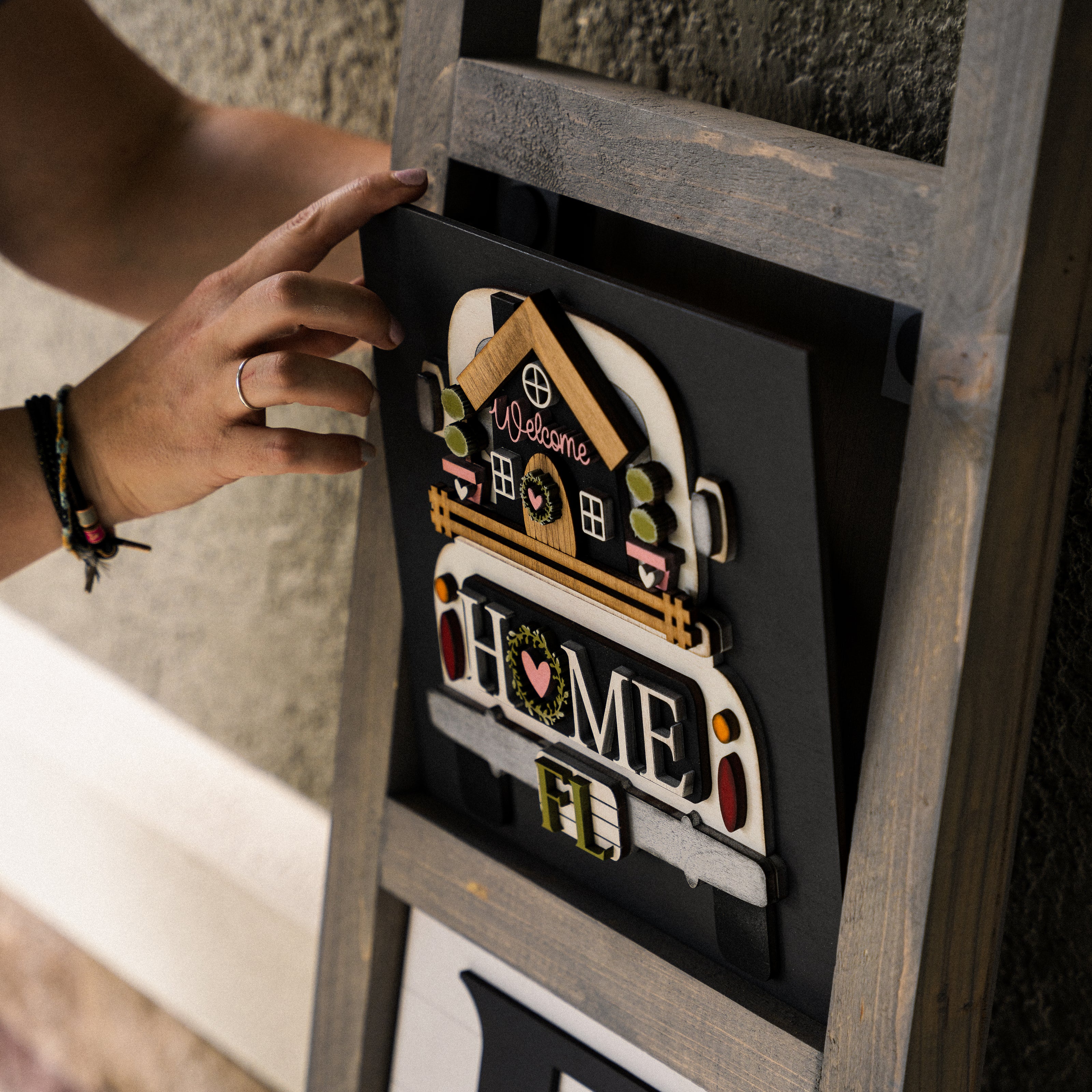 Swapping a hand-painted interchangeable porch tile on a wood ladder — Millie & Co.