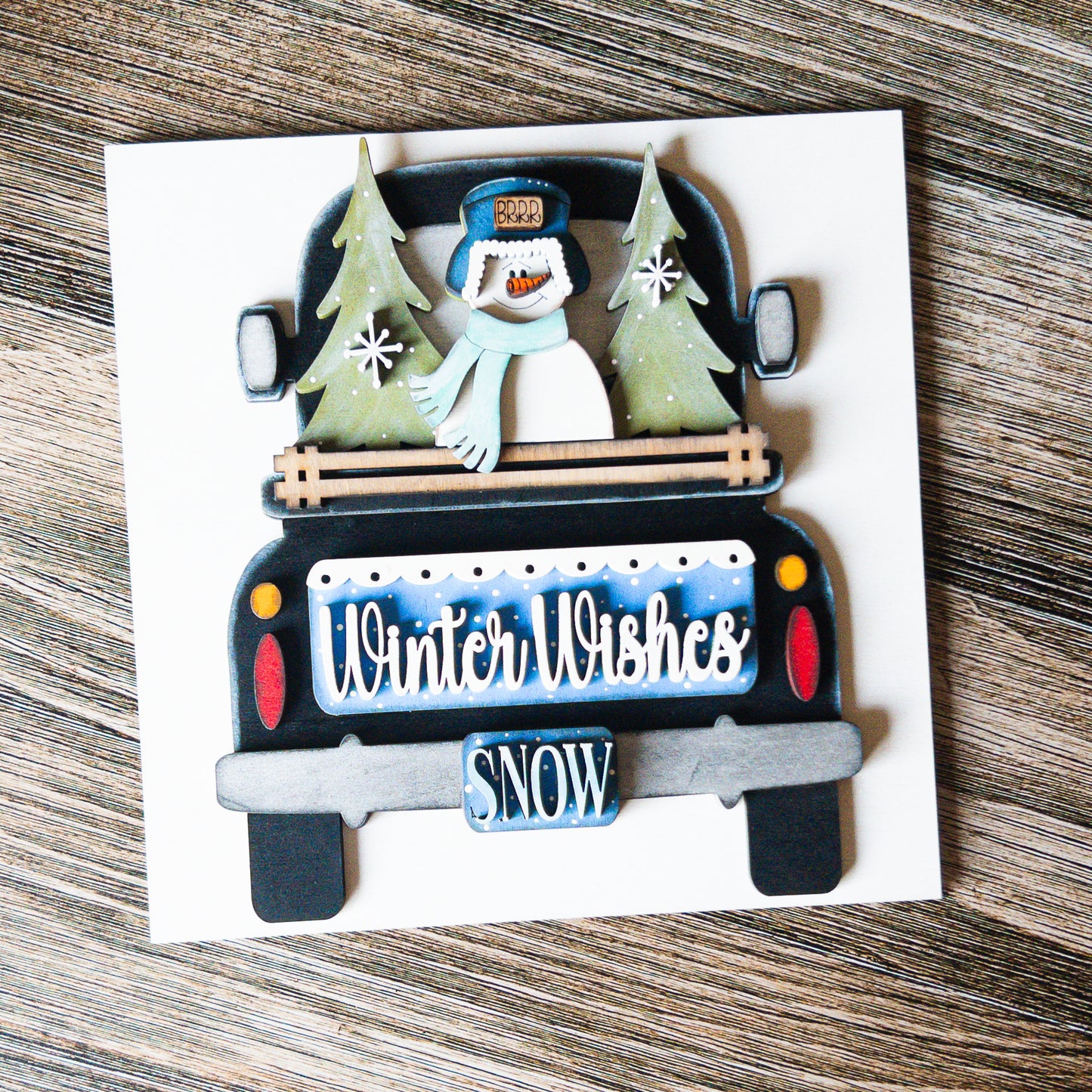 hand-painted interchangeable winter tile featuring a truck with trees and a snowman - Millie & Co.